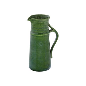 May include: A green ceramic jug with a wide mouth and a handle. The jug has a textured surface and a slightly rounded shape.