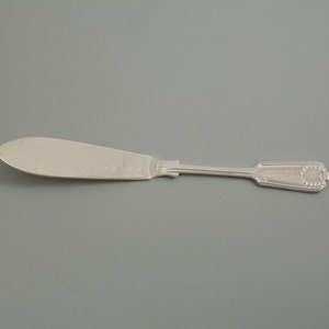 May include: A silver butter knife with a slightly curved blade and an ornate handle.