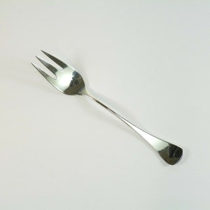 May include: A silver fork with a long, slender handle and three prongs. The fork is designed for serving food.