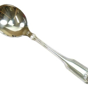 May include: A silver spoon with a rounded bowl and a long, detailed handle. The spoon has a decorative design at the end of the handle. The spoon is highly reflective, showing the surrounding environment.