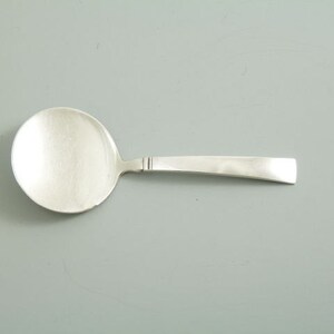 May include: A silver spoon with a rounded bowl and a long, slender handle.