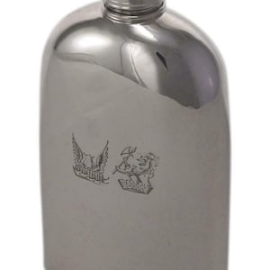 May include: A polished silver flask with a rounded body and a screw-on cap. The flask has a reflective surface and features two engraved crests. A classic and elegant accessory.