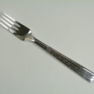 Può includere: Una forchetta d'argento con un motivo decorativo sul manico.