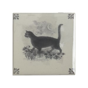 以下が含まれることがあります： 黒猫が三日月の下の庭を歩いているシルエットが描かれた正方形のセラミックタイル。 タイルはクリーム色の背景で、角には装飾的なアクセントがあります。