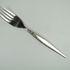 Könnte beinhalten: Eine silberne Gabel mit einem dekorativen Muster auf dem Griff.