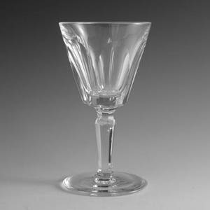 May include: A clear, stemmed glass with a wide, fluted bowl and a faceted stem. The glass sits on a round base. The glass is designed to hold liquid and is likely used for beverages.