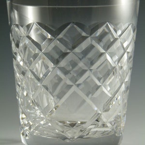 Pode incluir: Um copo de cristal transparente com um padrão de diamante. O vidro tem uma base espessa e uma borda lisa. Os cortes de diamante refletem a luz, criando um efeito brilhante. Esta elegante vidraria é adequada para servir bebidas.