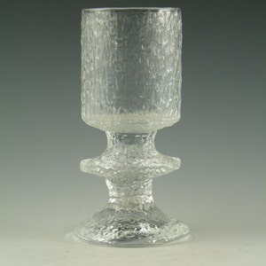 May include: A clear glass goblet with a textured surface and a wide base. The goblet has a unique design with a raised, textured ring around the middle.