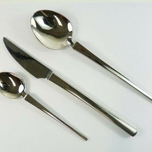 May include: A set of three silver-toned flatware pieces: a knife, a spoon, and a teaspoon. The knife has a sharp blade and a long handle. The spoon and teaspoon have rounded bowls and long handles.