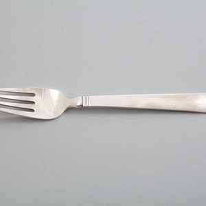 May include: A silver fork with a simple, sleek design. The fork has four tines and a smooth, rounded handle.