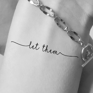 Könnte beinhalten: Ein temporäres Tattoo mit dem Schriftzug "let them" in Kursivschrift.