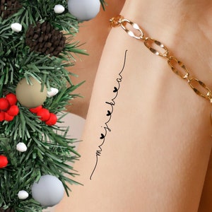 Peut inclure: Un poignet avec un bracelet en chaîne dorée et un petit tatouage qui dit "my heart beats for you" avec de petits cœurs.