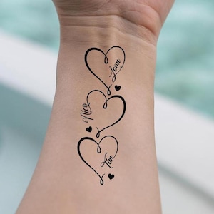 Puede incluir: Tres tatuajes negros en forma de corazón con los nombres Leon, Nico y Tim escritos dentro de cada corazón.