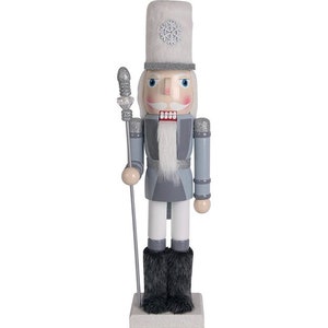 Może przedstawiać: Biało-szary drewniany łamacz orzechów z białym futrzanym kapeluszem i wzorem płatka śniegu. Łamacz orzechów trzyma srebrną laskę i ma białą brodę i wąsy.