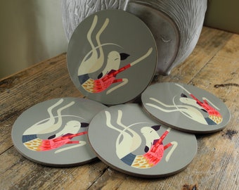 Puede incluir: Conjunto de cuatro posavasos redondos grises con una ilustración de un perro blanco en cada uno. El perro está en una pose juguetona con un diseño estampado rojo y amarillo.