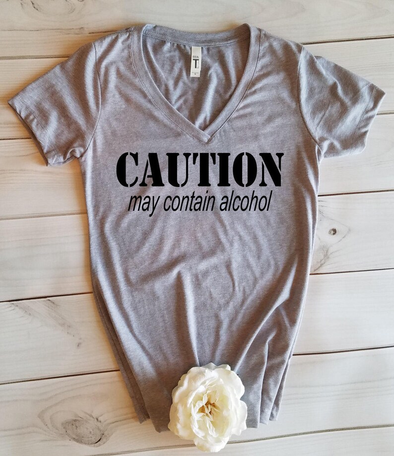 May include: Gray V-neck t-shirt with the text "CAUTION may contain alcohol" printed in black.