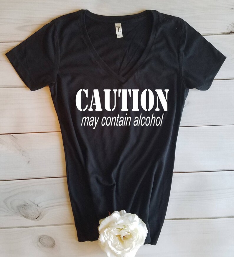 May include: Black v-neck t-shirt with white text that reads "CAUTION may contain alcohol".