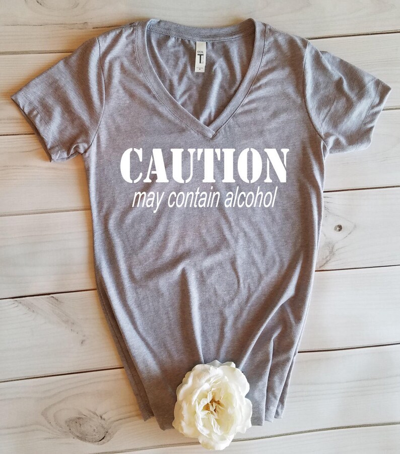 May include: Gray V-neck t-shirt with the text "CAUTION may contain alcohol" printed in white.