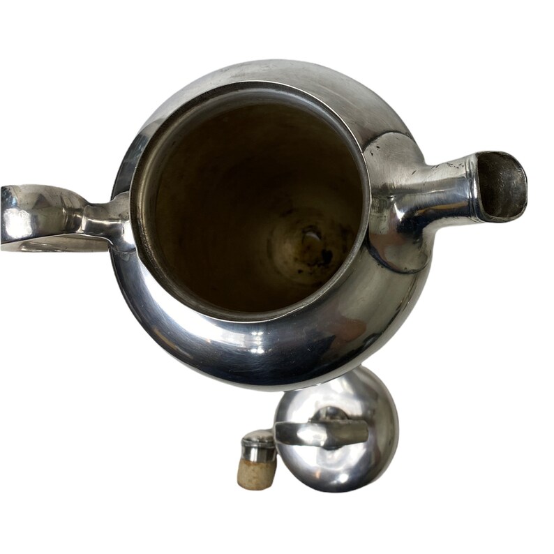 May include: A silver teapot with a rounded body, spout, and handle. The lid and a small stopper are next to the teapot. The interior of the teapot is visible, showing a dark interior. The teapot is on a white background.