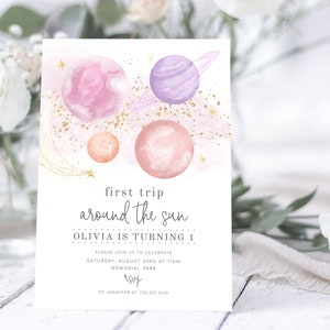 May include: A pink and purple watercolour illustration of planets and stars with gold glitter. The text reads "first trip around the sun Olivia is turning 1 Please join us to celebrate Saturday, August 23rd at 11am Memorial Park rsvp to Jennifer at 730.231.3123"