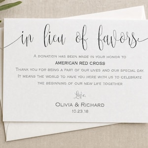 May include: A white rectangular card with black text reading in lieu of favors, a donation has been made in your honor to American Red Cross, thank you for being a part of our lives and our special day, love, Olivia & Richard, 10.23.18.