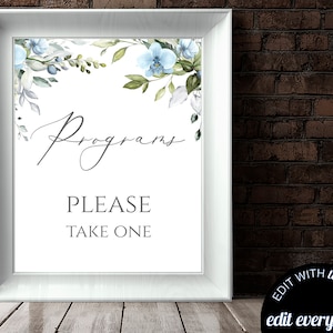 Puede incluir: Un letrero enmarcado con la palabra "Programs" en escritura elegante y el texto "PLEASE TAKE ONE" en una fuente sencilla. La parte superior del letrero está decorada con flores azules de acuarela y hojas verdes. El marco es blanco y el fondo es una pared de ladrillos.