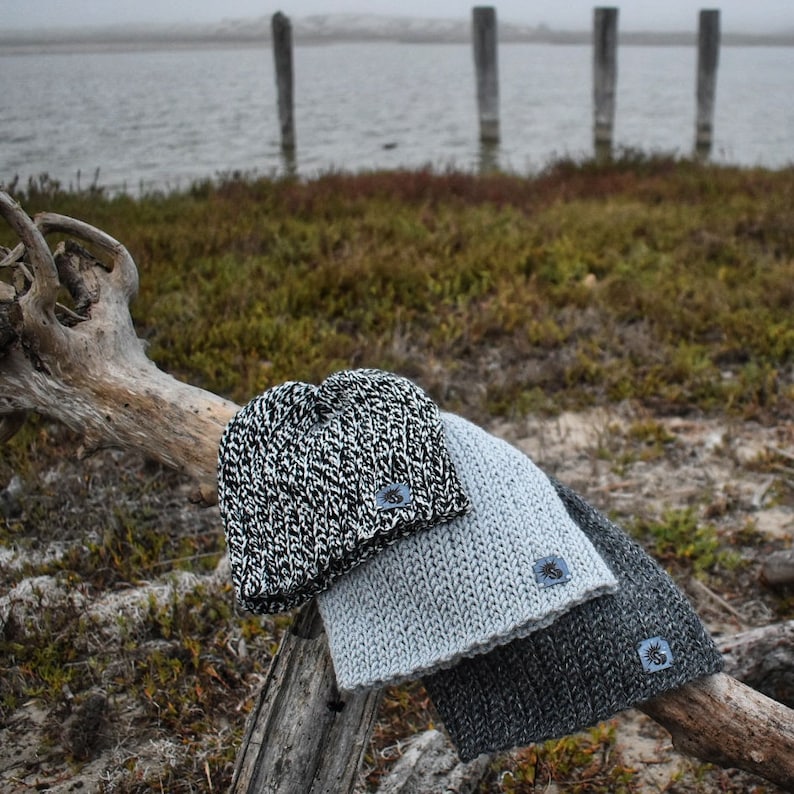 May include: Three knitted hats in different colors and patterns. The hats are stacked on top of each other on a wooden branch. The hats are all made of a soft, warm yarn.
