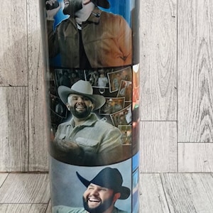 May include: A black and silver tumbler with a collage of photos of a country music singer wearing a cowboy hat. The photos are arranged in a grid pattern.