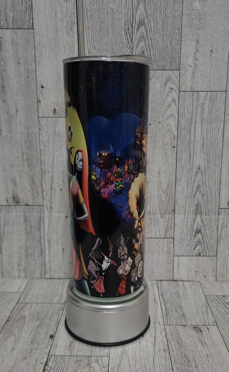 Puede incluir: Un vaso de acero inoxidable con fondo negro y una imagen colorida de personajes de la pel&iacute;cula "Pesadilla antes de Navidad".