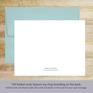 May include: A blank white rectangular card positioned in front of a light blue envelope. The back of the card features the black text SIMPLY INVITING and the website address www.shopsimplyinviting.com centered at the bottom edge.