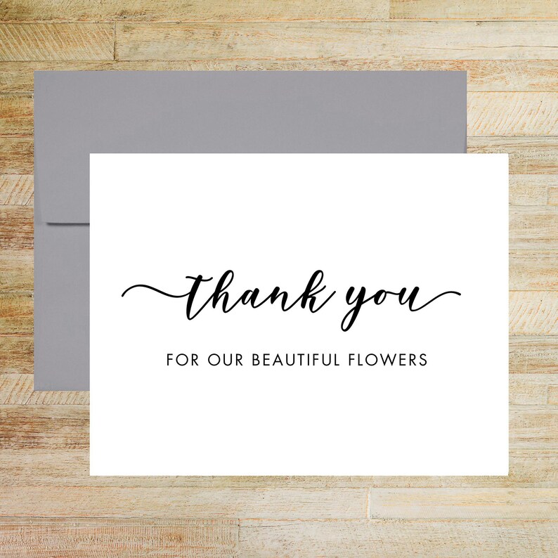 May include: A white rectangular greeting card with a grey envelope. The card features the black text "thank you" in a cursive script font, followed by the text "FOR OUR BEAUTIFUL FLOWERS" in a simple, clean, black sans-serif typeface.
