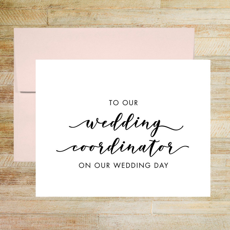 May include: A white card with black text that reads "To our wedding coordinator on our wedding day".