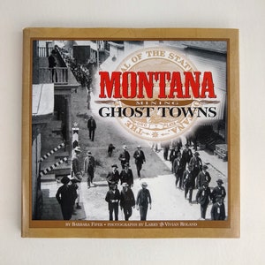 May include: A book titled "Montana Mining Ghost Towns" with a sepia-toned image of a street scene with people. The book cover has a gold border and features the state seal of Montana. The title is in red and black lettering.