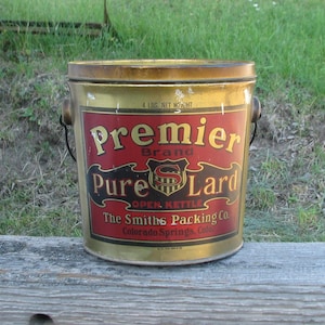 May include: Vintage Premier Brand Pure Lard tin with a gold and red label. The label reads "Premier Brand Pure Lard" and "The Smiths Packing Co. Colorado Springs, Colo." The tin has a black handle and is marked "4 LBS. NET WEIGHT."