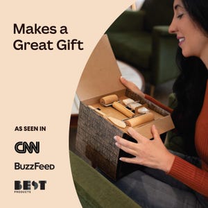 May include: A person opens a gift box containing a set of wooden tools for crafting. The box is brown with a black and white patterned design. The tools include rolling pins, a scraper, and a wooden knife.