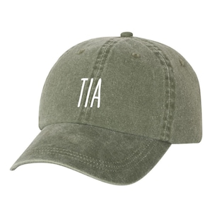 May include: A green, washed cotton baseball cap with the word "TIA" embroidered in white on the front.