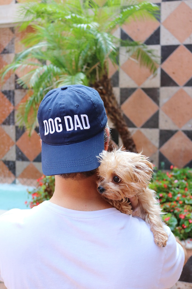 Dog dad hat with slightly curved design holding a puppy.
