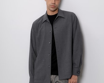 May include: A gray long-sleeved shirt with a button-up front and a patch pocket on the left side. The shirt is made of a textured fabric and has a relaxed fit.