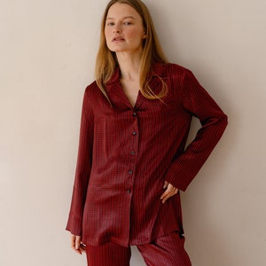 May include: A red and black checked pyjama set with a collared shirt and long trousers.