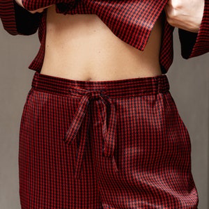 May include: Red and black patterned pyjama trousers with a drawstring waist.
