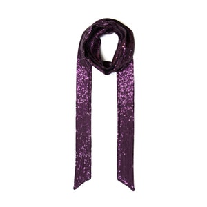 Peut inclure: Une écharpe en sequins violette avec un design long et fluide. L'écharpe est faite d'un tissu doux et chatoyant, parfait pour ajouter une touche de glamour à n'importe quelle tenue.