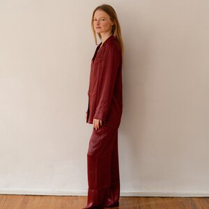 May include: A woman wearing a red and black checked pyjama set. The set includes a long-sleeved shirt and matching trousers.