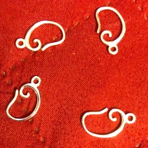 May include: Four silver earring hooks with a decorative swirl design. The hooks are shown against a red fabric background. These earring findings are ready for jewellery making.