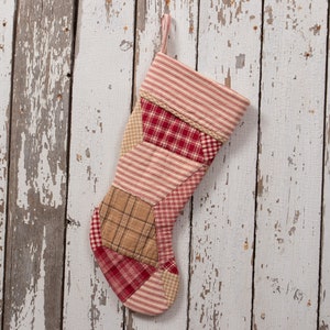 May include: A red, white, and brown patchwork Christmas stocking with a white fabric loop at the top.
