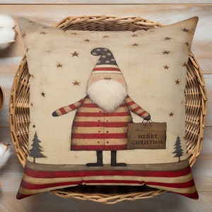 May include: A decorative pillow with a vintage-style illustration of a Santa Claus wearing a red and white striped coat and holding a bag that says "Merry Christmas". The background is beige with red and white stripes at the bottom and stars scattered throughout.