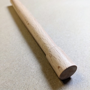 May include: A wooden dowel rod with a rounded end. The dowel is light brown in colour and has a smooth finish.
