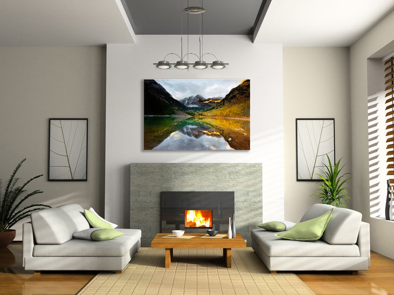 May include: A living room interior with a fireplace, two sofas, and a coffee table. A large framed photograph of a mountain lake with fall foliage and snow-capped peaks hangs above the fireplace.