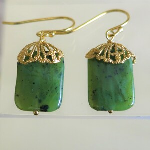 K&ouml;nnte beinhalten: Ein Paar goldene Ohrringe mit gr&uuml;nen Jade-Steinen. Die Ohrringe haben ein filigranes Design.