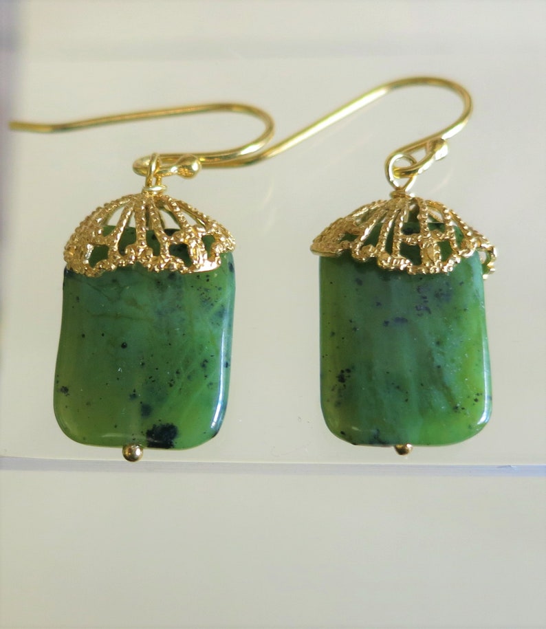K&ouml;nnte beinhalten: Ein Paar goldene Ohrringe mit gr&uuml;nen Jade-Steinen. Die Ohrringe haben ein filigranes Design.