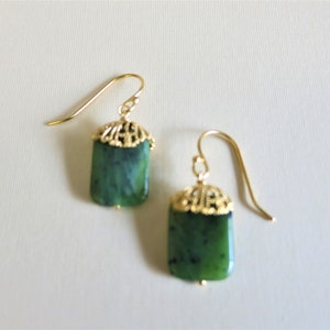 K&ouml;nnte beinhalten: Ein Paar goldene Ohrringe mit gr&uuml;nen Jade-Steinen. Die Ohrringe haben ein filigranes Design.